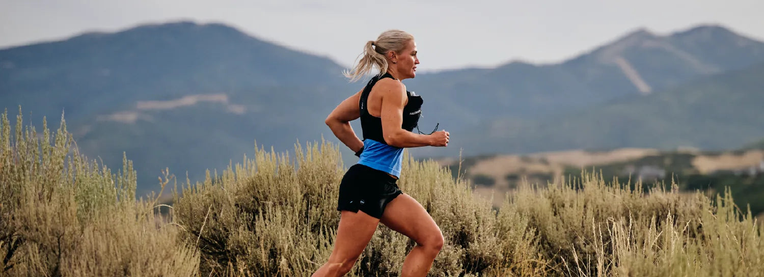 Trail runner moving through sagebrush with mountains behind