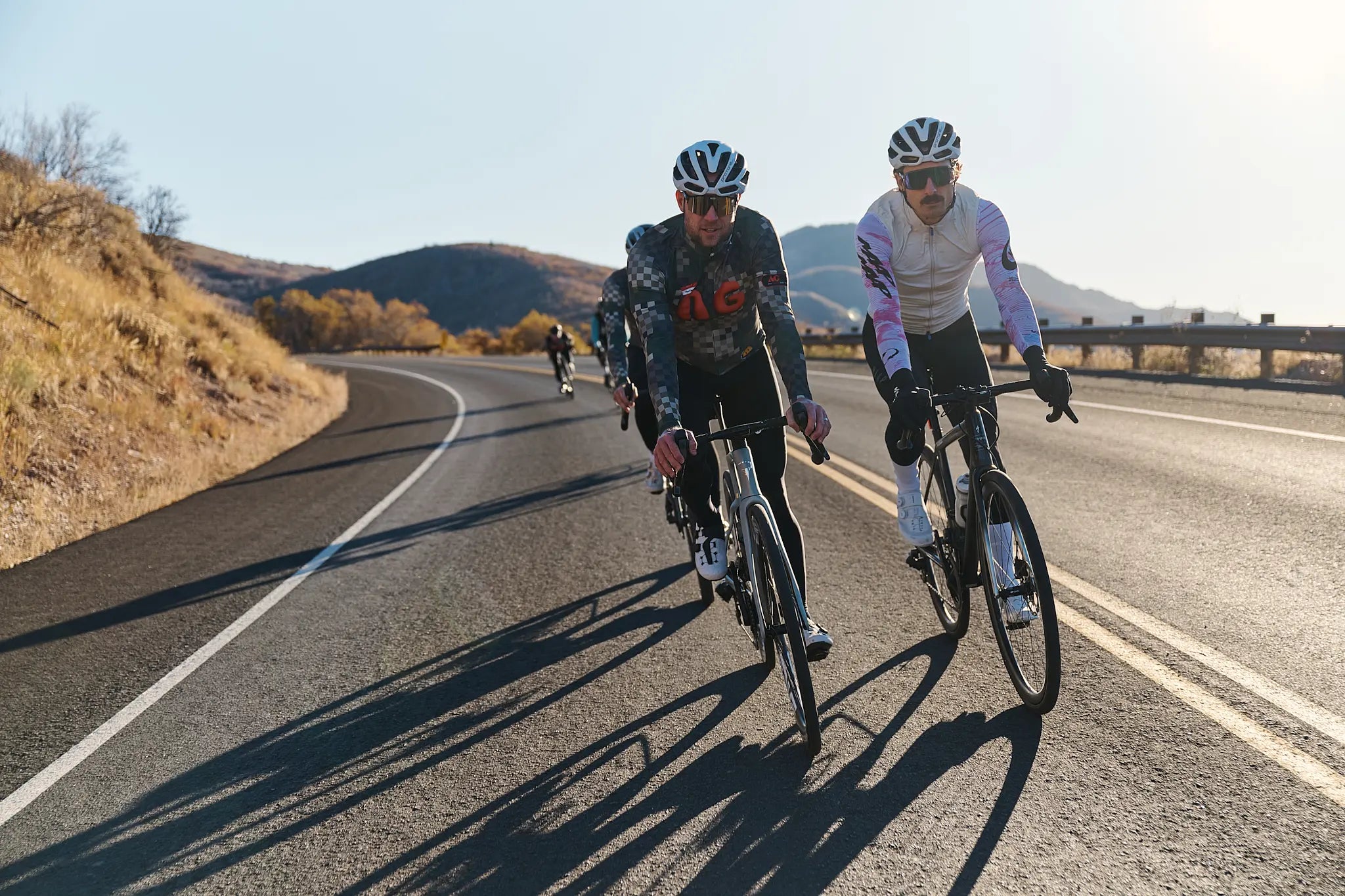 Two cyclists riding on a road with mountains in the background