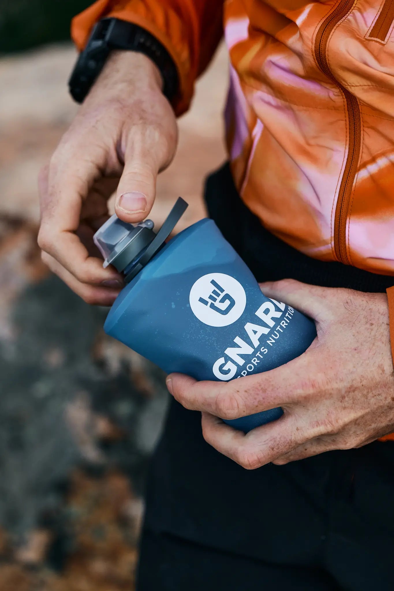 Trail runner opening a collapsible blue Gnarly Stowe Bottle
